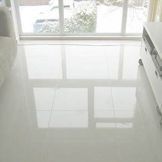 a living room with white tile floors and large windows