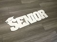 the word senior spelled in white paper on a wood floor