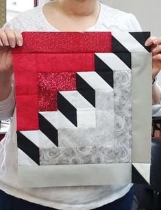 a woman holding up a piece of art that is made from paper and fabric,