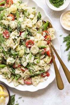 a plate full of pasta salad with lemon wedges and parsley on the side