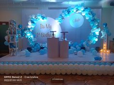 a stage set up for a birthday party with blue balloons and white pillars on it