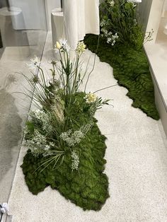 the bathroom is decorated with green moss and white flowers in vases on the floor