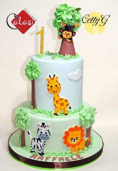 a three tiered cake with animals and trees on the top is decorated in green icing