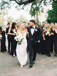 a bride and groom walking with their bridal party