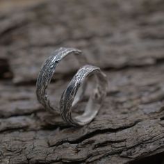 two silver rings sitting on top of a piece of wood