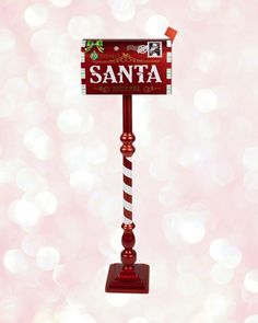 a santa mailbox on top of a red pole with a candy cane in it