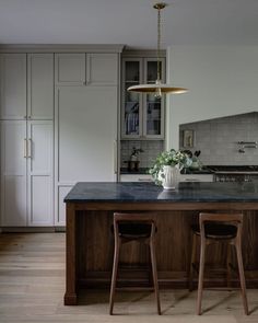 a kitchen with two bar stools next to an island in the middle of it