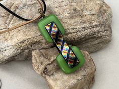 a green beaded necklace sitting on top of a rock next to a stone slab