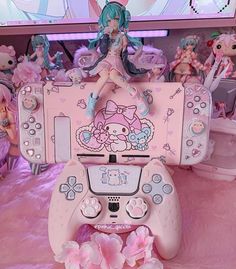 a pink hello kitty video game console sitting on top of a bed covered in toys