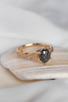 a gold ring with a black diamond in it sitting on a white piece of wood