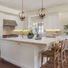 a large kitchen with white cabinets and an island