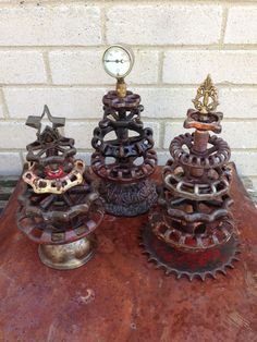 three metal objects sitting on top of a table next to a brick wall and clock