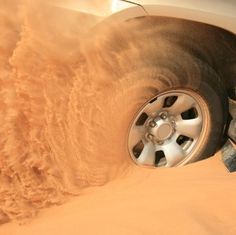 a car driving in the sand with it's tire sticking out from under its wheel