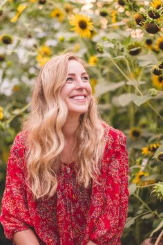 a woman standing in front of sunflowers smiling