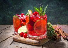 two glasses filled with cranberry lemonade and rosemary garnish on top of a cutting board