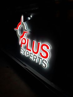 the sign for plus experts is lit up in the dark with red and white letters