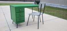 a green desk and chair sitting on the sidewalk