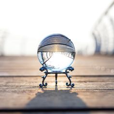 a glass ball sitting on top of a wooden table next to a metal stand with a mirror in it