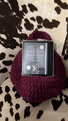 a book sitting on top of a red bag next to a black and white animal print chair