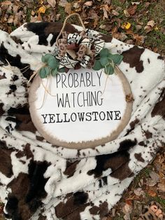 a sign that says, probably watching yellowstone on the ground with leaves around it