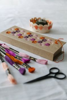 some crafting supplies are laying out on a white tablecloth with scissors and thread