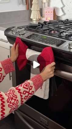 a woman is cleaning the oven with her red mitt and cloth in front of it