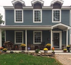 a blue house with lots of windows and flowers in the front yard on a cloudy day