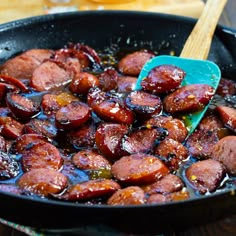 a skillet filled with cooked sausages on top of a wooden table