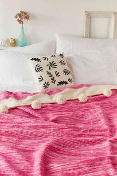 a bed with white pillows and pink bedspread