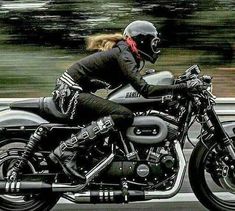 a woman riding on the back of a motorcycle down a road with trees in the background