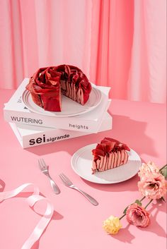 a pink table topped with two white plates and a cake on top of a box