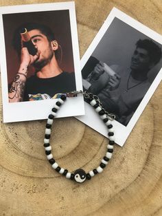 two photographs and a bracelet with a man's face in the middle, on top of a wooden table