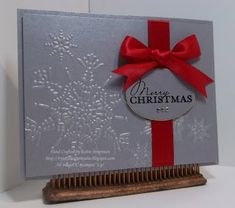 a christmas card with a red ribbon on it and a wooden comb next to it