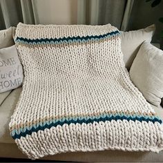 a crocheted blanket sitting on top of a couch next to pillows and a pillow