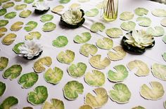 green and white paper flowers on a table with water lilies in the background,