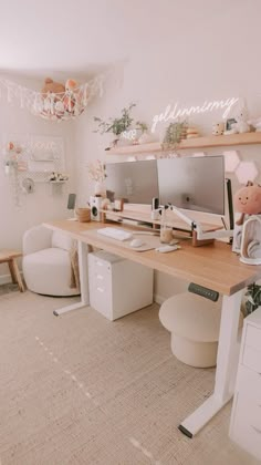 a desk with two computer monitors on top of it next to a white chair and ottoman