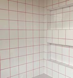 a bathroom with red and white tiles on the walls, shelves in the shower stall