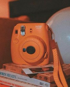 an orange camera sitting on top of some books