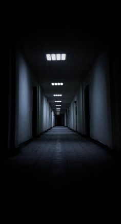 an empty hallway with light coming from the ceiling and lights shining down on the floor