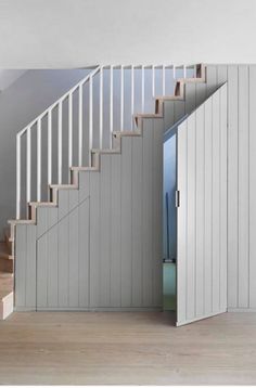 an open door leading up to a white stair case in a room with wooden floors