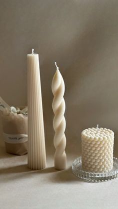 a white candle sitting next to a glass plate and some other items on a table