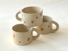 three coffee mugs with apples on them sitting next to each other in front of a white background