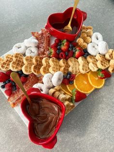 a plate topped with waffles and fruit next to a bowl filled with chocolate