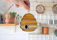 a hand holding a stained glass ornament in the shape of a beehive