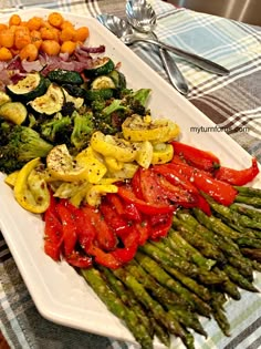 asparagus, tomatoes, broccoli and other vegetables on a white platter