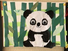 a panda bear made out of paper on top of a green and white background with bamboo leaves