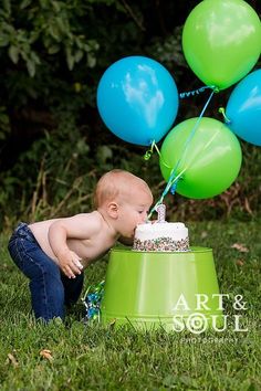 a baby is playing with some balloons in the grass