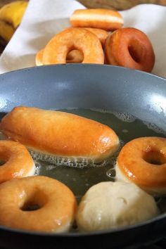 donuts are being cooked in a frying pan