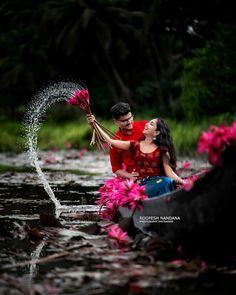 a man and woman in a boat with pink flowers splashing out of the water