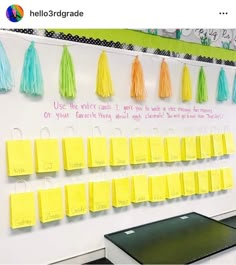 a bulletin board with yellow sticky notes and tassels hanging on it's sides